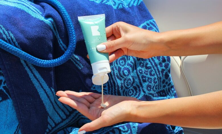 Persona aplicando crema solar en la playa