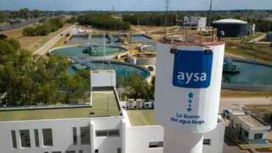 Imagen de una persona sosteniendo un vaso de agua potable, con un fondo de una planta de tratamiento de agua