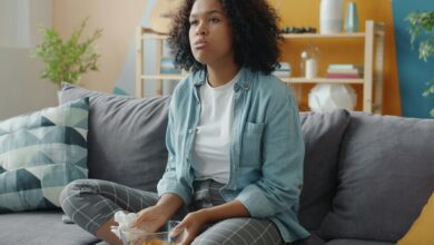 Persona sentada frente a una computadora, con una expresión de aburrimiento