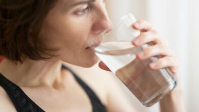 Una persona bebiendo agua con una expresión de relajación en un entorno natural