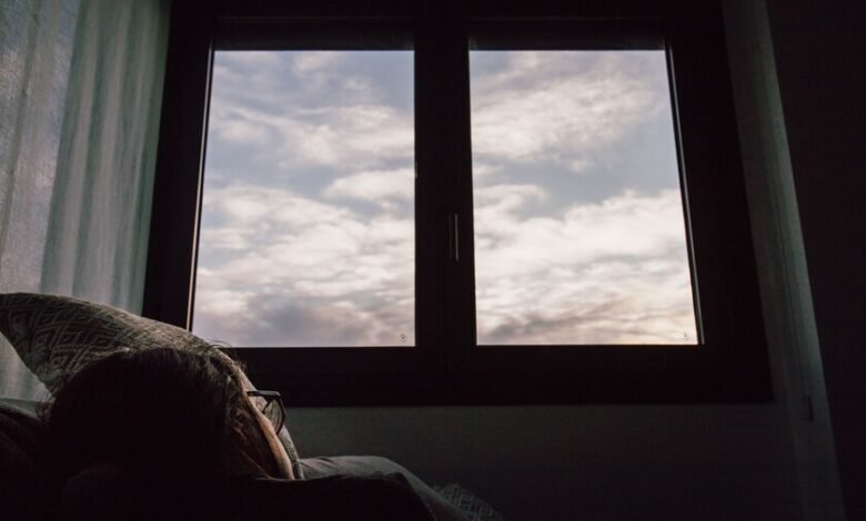 Persona durmiendo en una cama con la ventana abierta