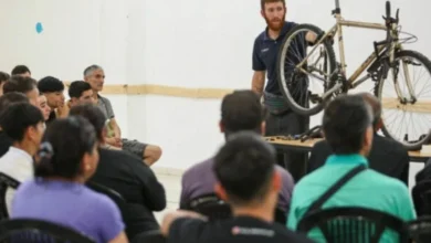 Persona reparando una bicicleta con herramientas en una mesa de trabajo