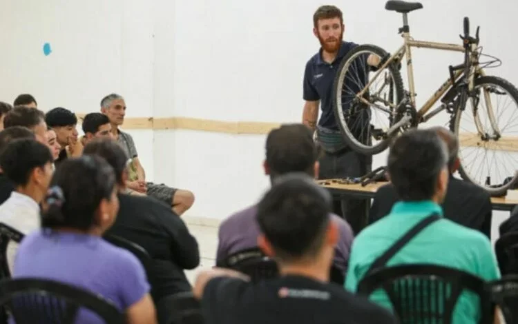 Persona reparando una bicicleta con herramientas en una mesa de trabajo