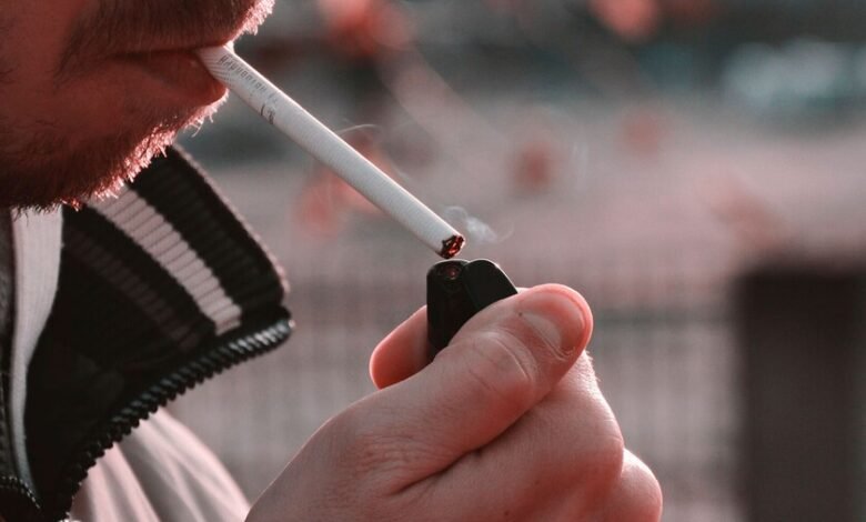 Persona sosteniendo un cigarro mientras mira pensativa