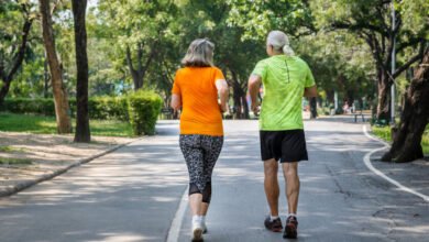 Persona mayor caminando rápido en parque, simbolizando salud y longevidad