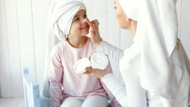 Niña aplicándose crema facial rodeada de productos de belleza
