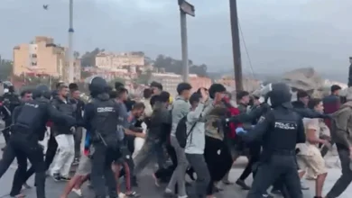 Migrantes en fila frente al puerto de Ceuta mientras la policía los traslada al nuevo campamento
