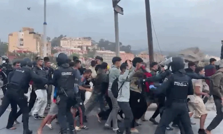 Migrantes en fila frente al puerto de Ceuta mientras la policía los traslada al nuevo campamento